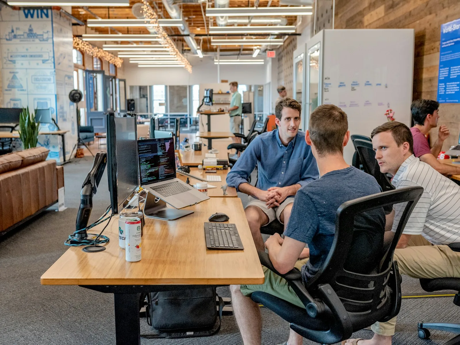 Colleagues in conversation at their desks in an open office