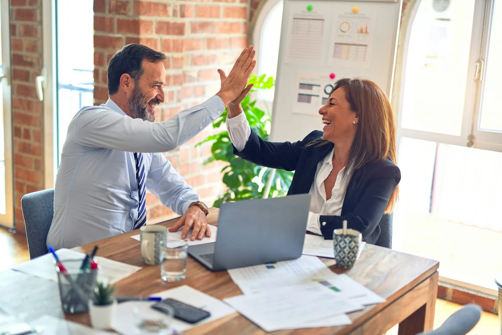 Two colleagues celebrating progress together at their desk