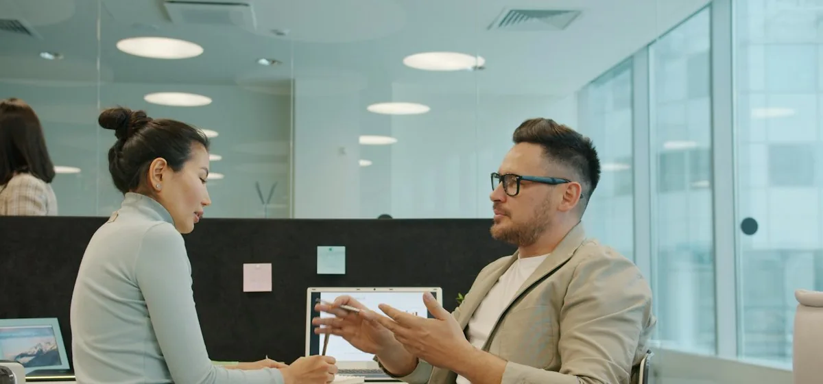 Two colleagues discussing questions at a shared desk
